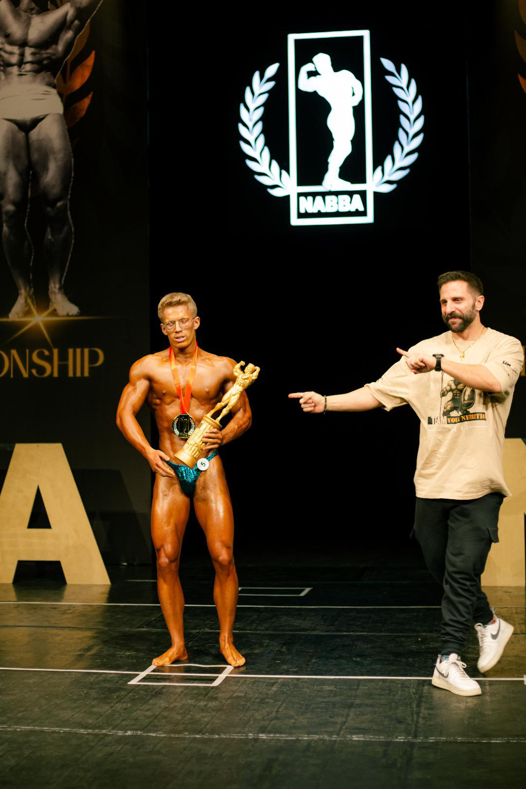 Marco Strub auf der Bühne mit Athlet, Pokal und Coaching Erfolg